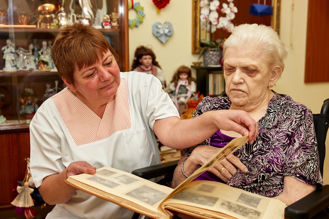 Eine Pflegerin und eine Bewohnerin schauen sich ein Fotoalbum in der avendi-Einrichtung PARKSTRASSE an