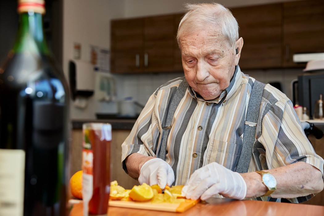 Ein Bewohner der avendi Einrichtung PARKSTRASSE nimmt an der Kochgruppe teil und schneidet eine Orange